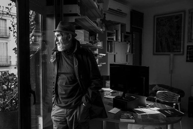 Ángel Alonso apoyado en el quicio de la puerta de su estudio, con estanterías y una mesa de trabajo al fondo