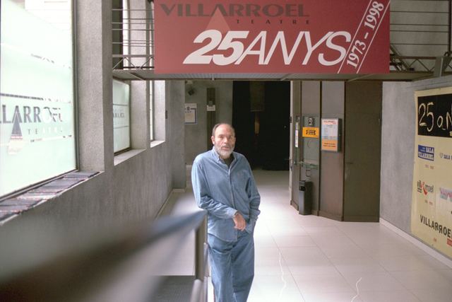 Ángel Alonso camina por el vestíbulo del Villarroel Teatre bajo una pancarta que dice VILLARROEL 25 ANYS 1973-1998